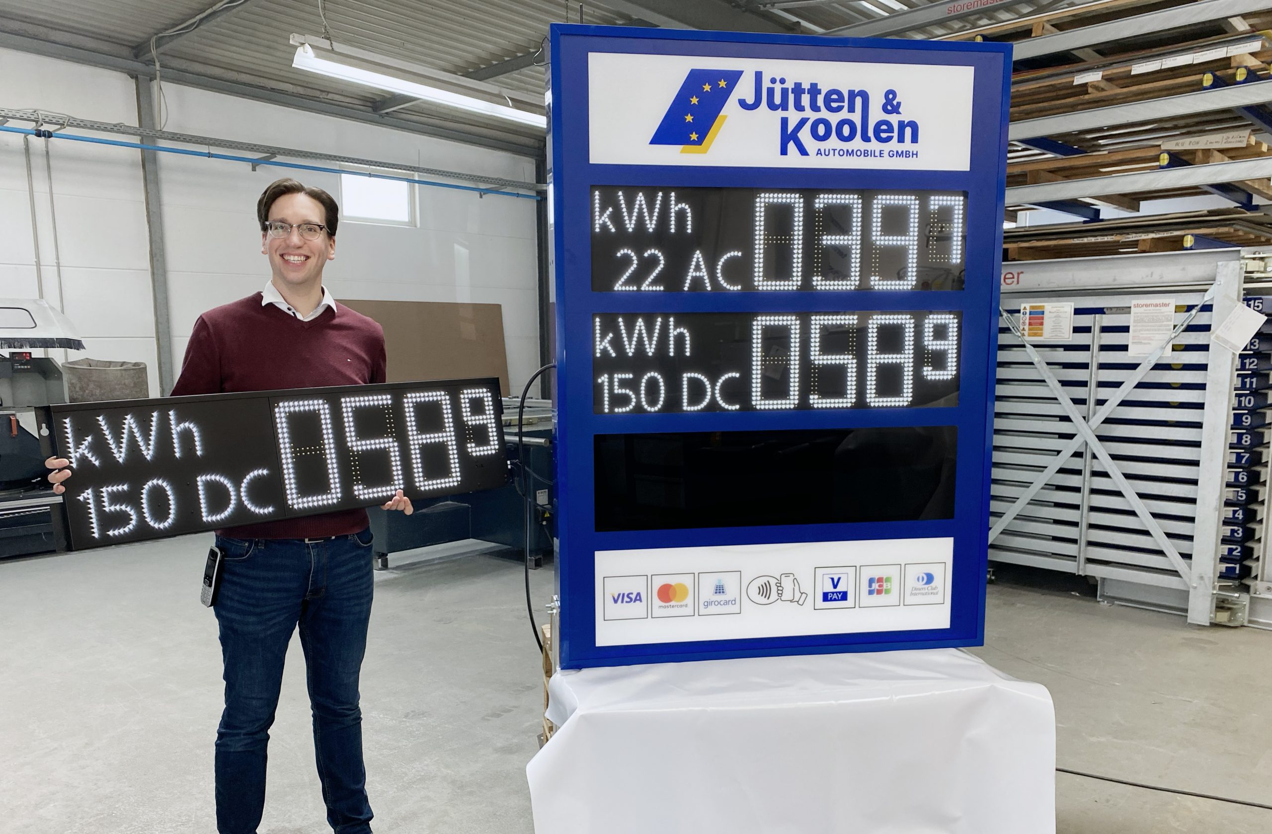 Rene Rudolph präsentiert die erste Preisanzeige für Ladestrom in Deutschland. Der Preis wird in kWh angezeigt.